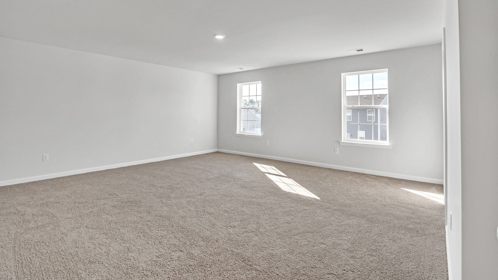 upstairs bedroom with neutral carpet, spacious closets and large windows