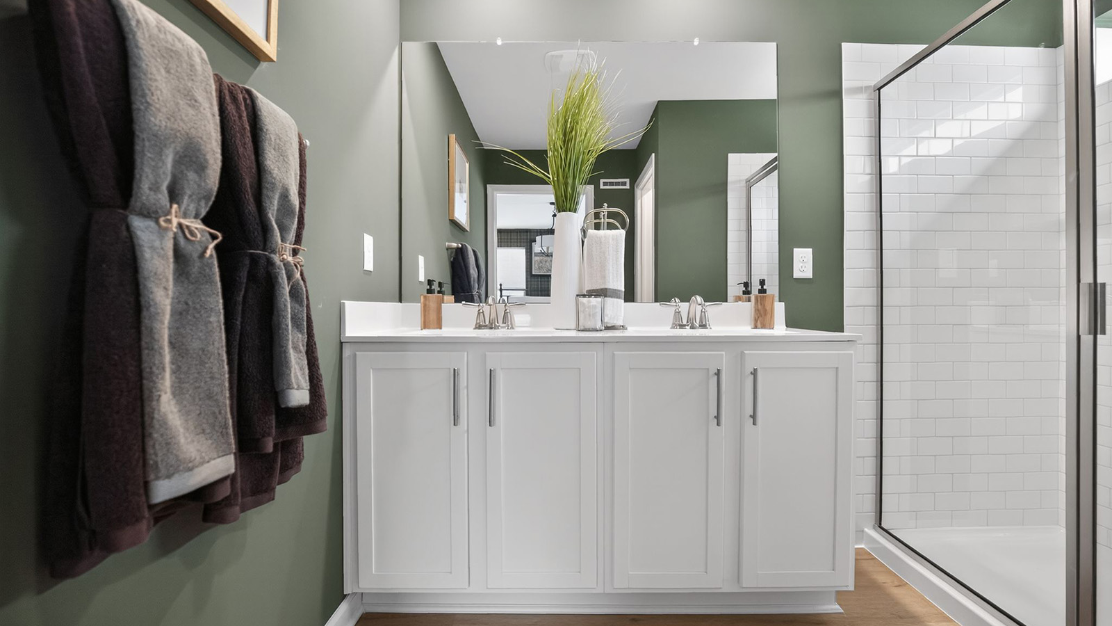 spacious full bathroom with modern design and sage green walls throughout and double vanity