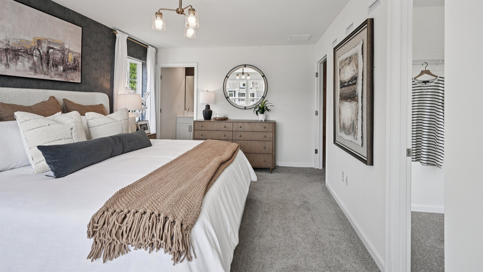 primary bedroom with large windows, walk in closet and full bath with double vanity