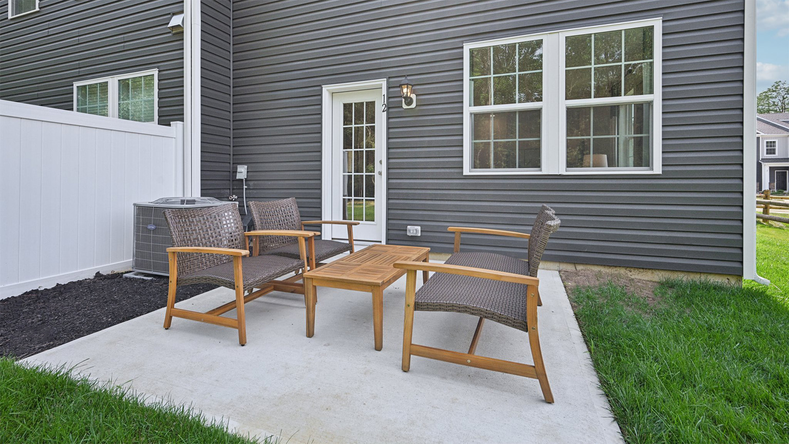outside patio with green spaces, fence and seating area