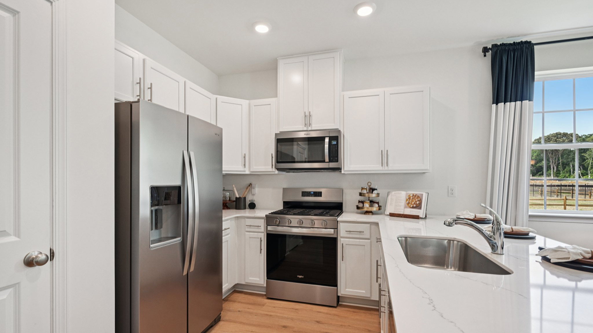 spacious kitchen with large island, white cabinetry, and light wood floors