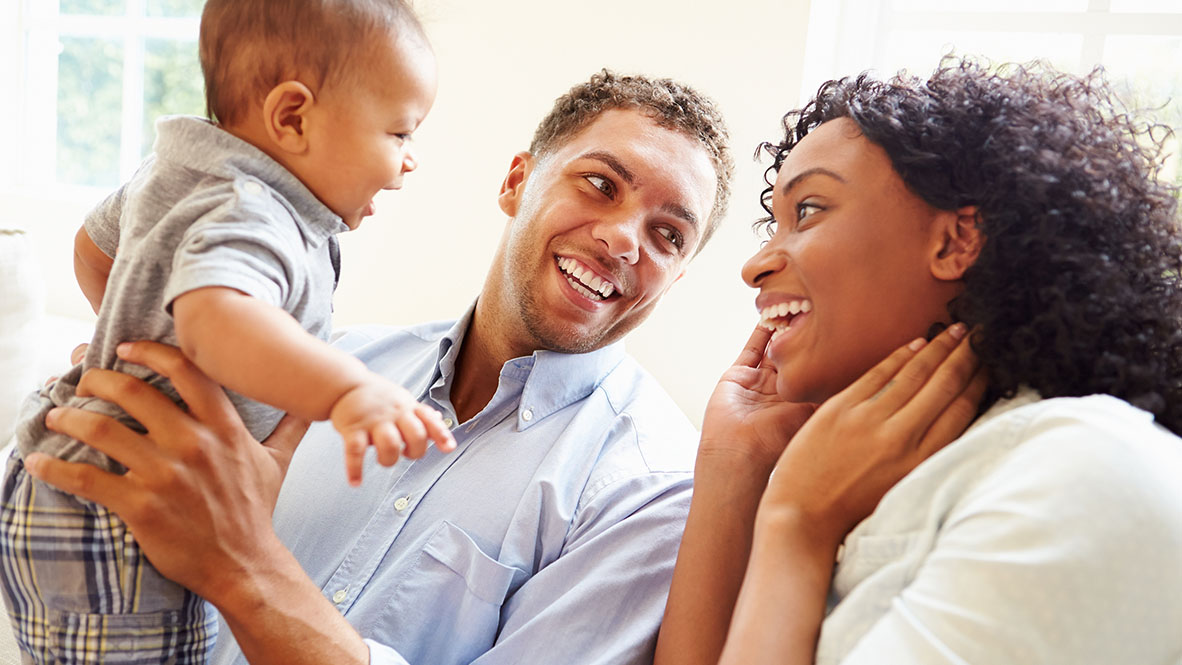 lifestyle photo of a family smiling with their baby