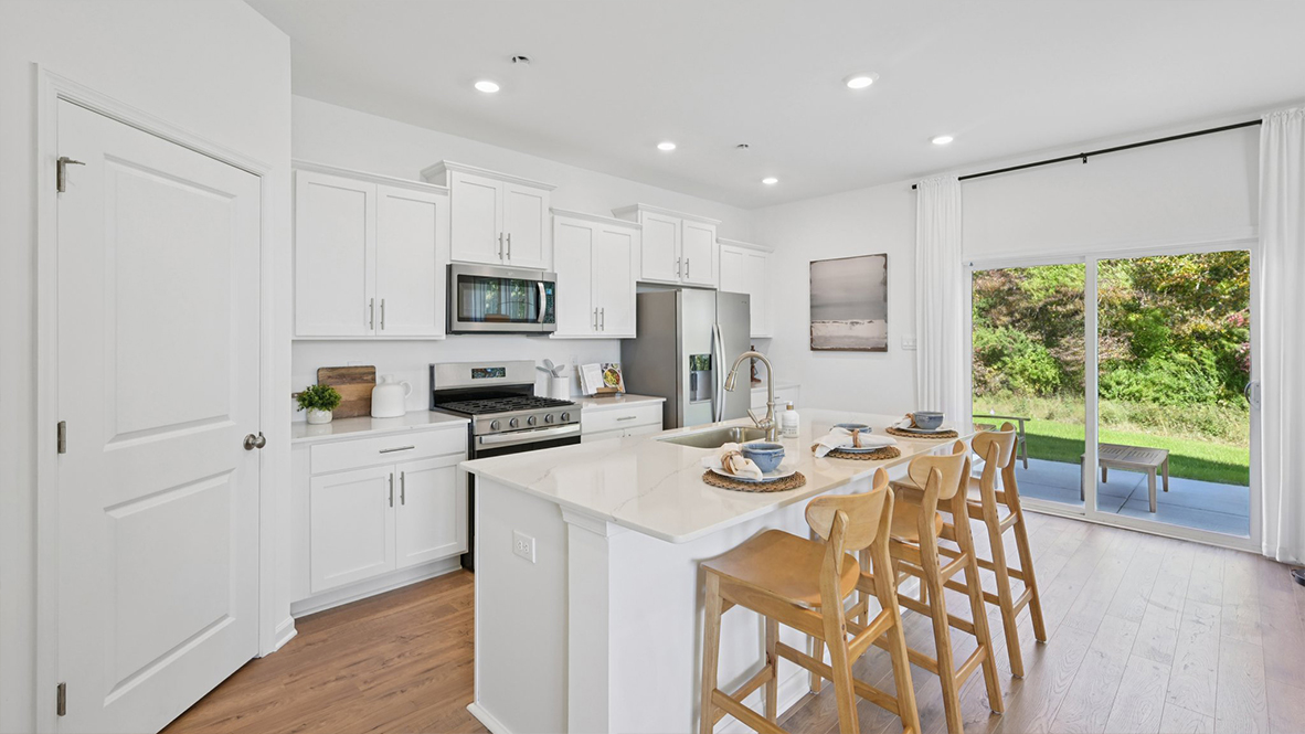 beautiful and spacious kitchen quartz island with white cabinetry and stainless steel appliances