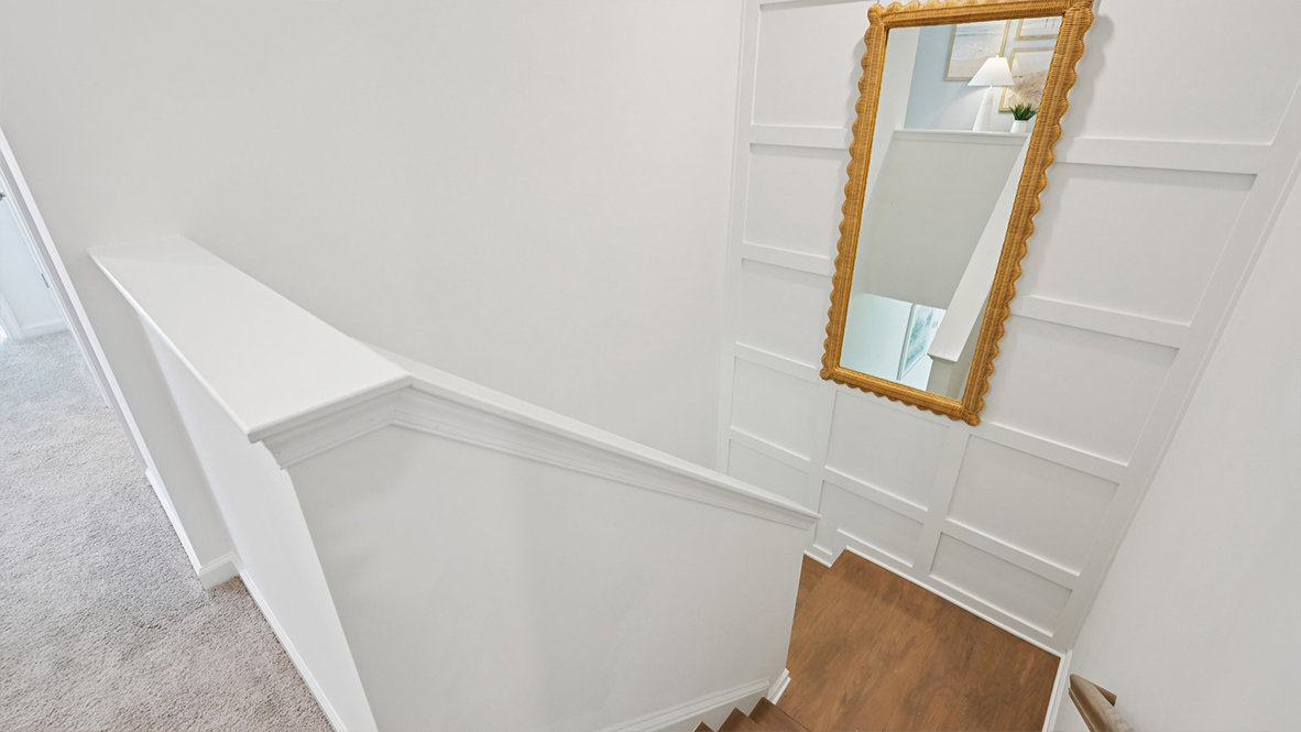 stairs leading up to the second floor with gold accent mirror