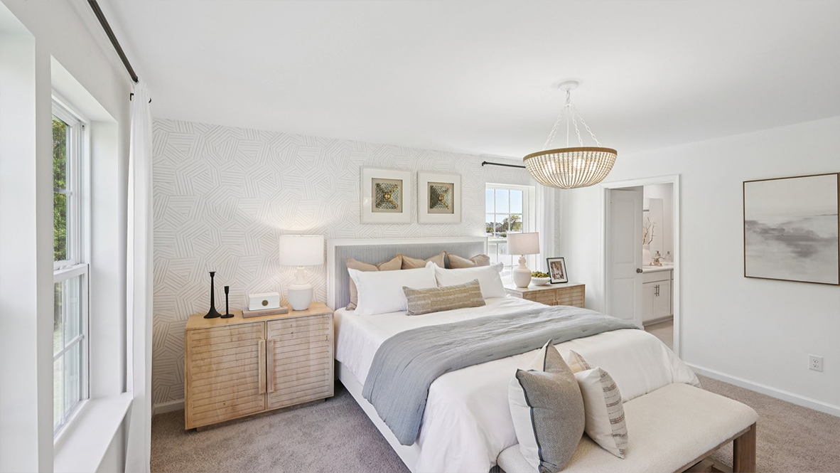spacious primary suite with neutral tones throughout, large windows, and a beautiful light fixture