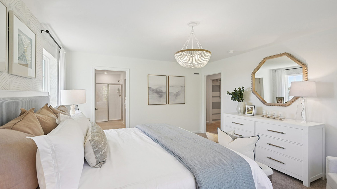 spacious primary suite with neutral tones throughout, large windows, and a beautiful light fixture