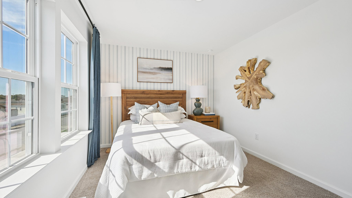 spacious bedroom with neutral tones and blue accents and large windows