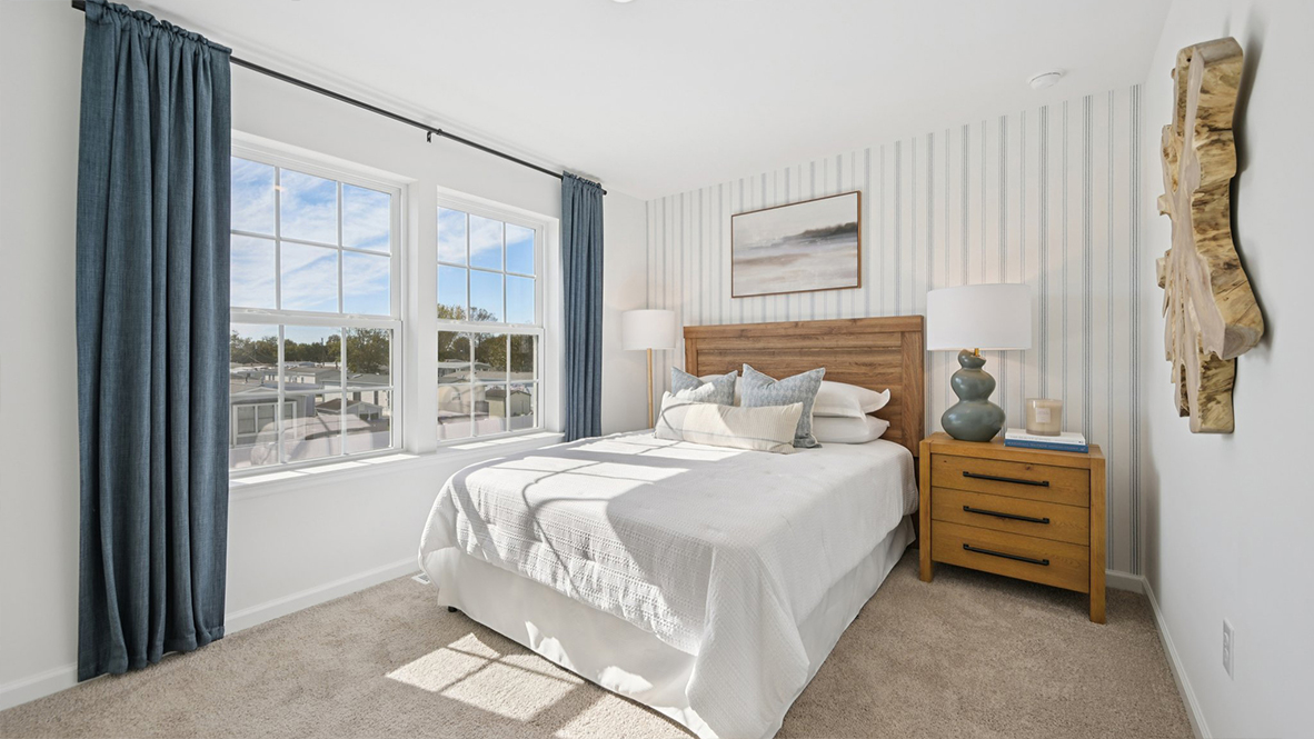 spacious bedroom with neutral tones and blue accents and large windows