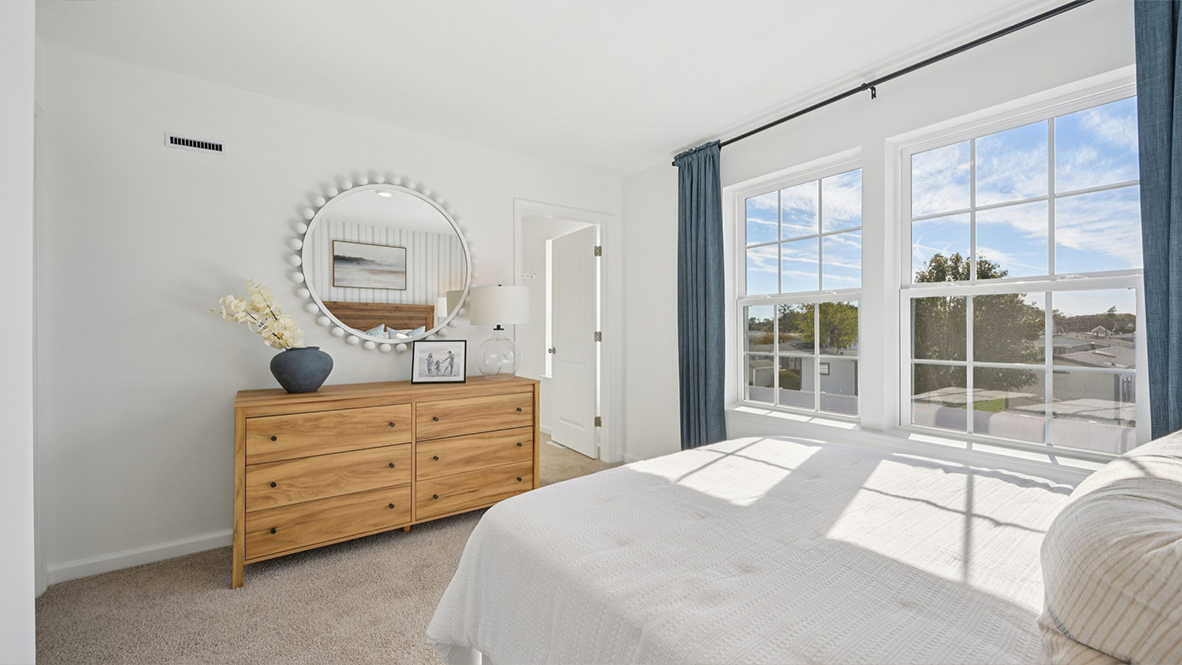 spacious bedroom with neutral tones and blue accents and large windows