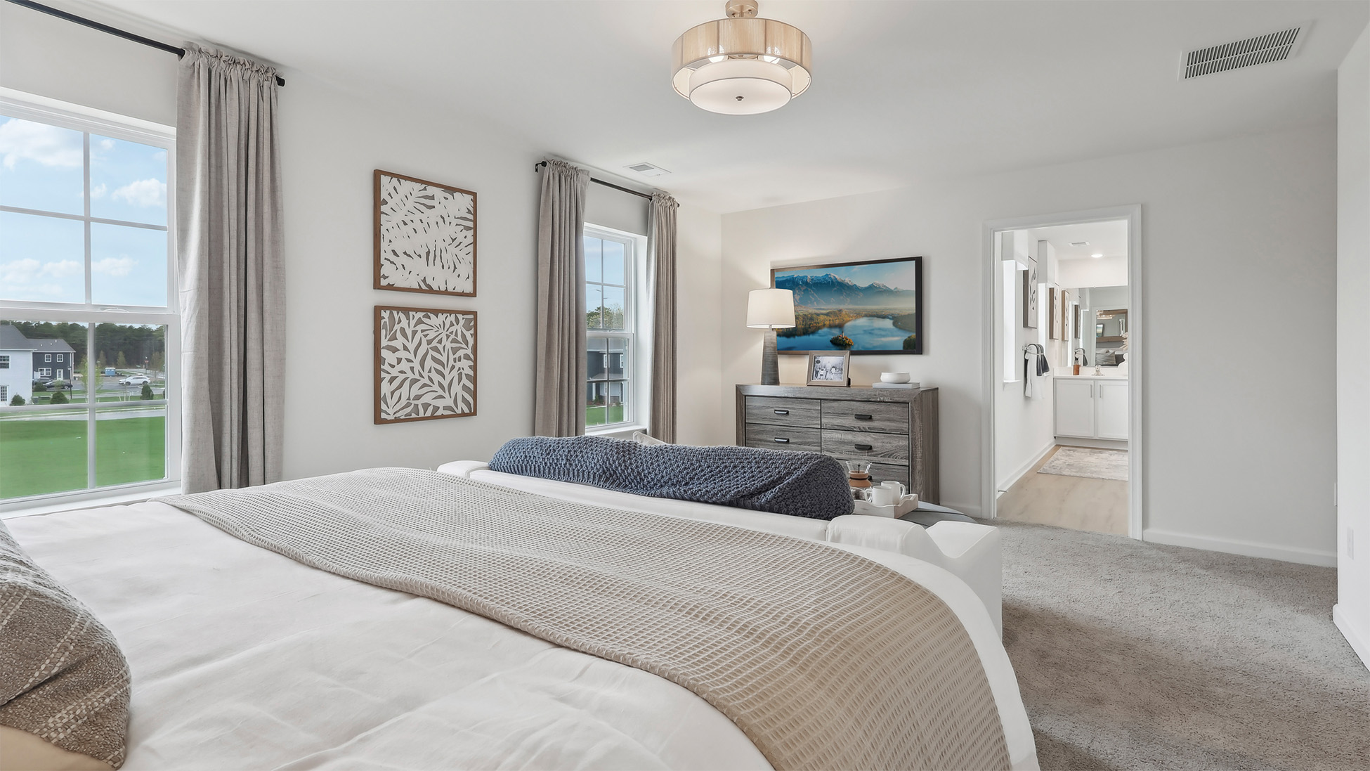 primary suite with light fixture, full bath, and large walk in closet
