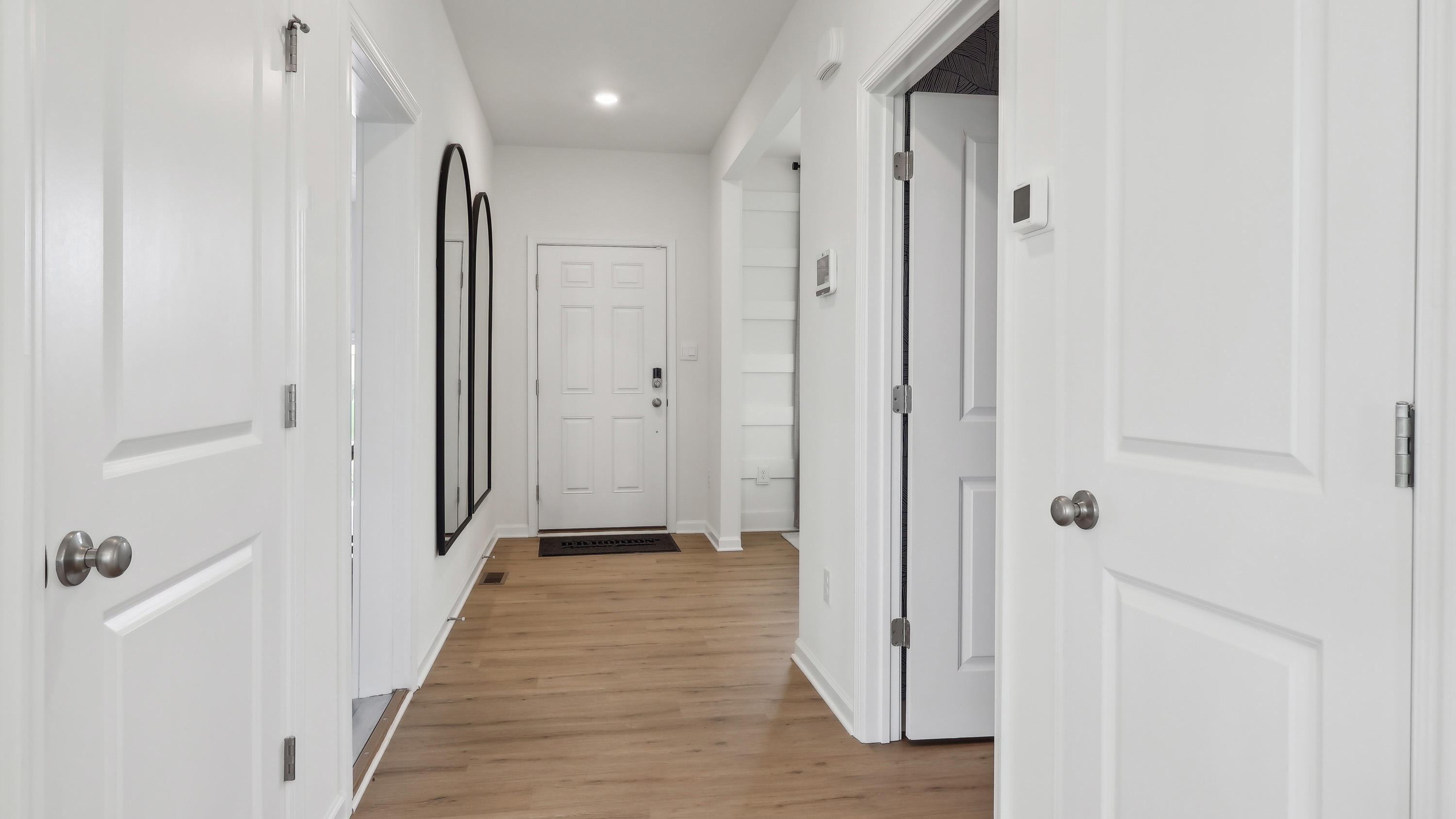 hallway with light wood floors leading to the main floor living area