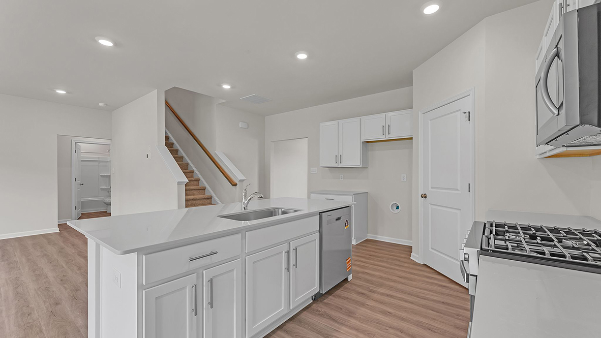 large kitchen with spacious white quartz island and white cabinetry