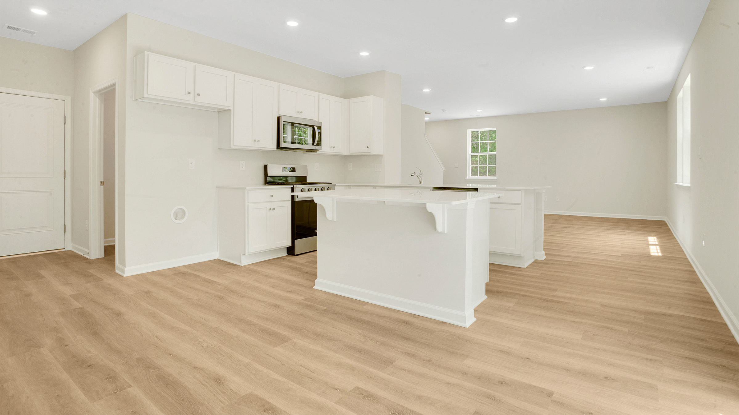 large kitchen island and modern appliances with open concept living room behind