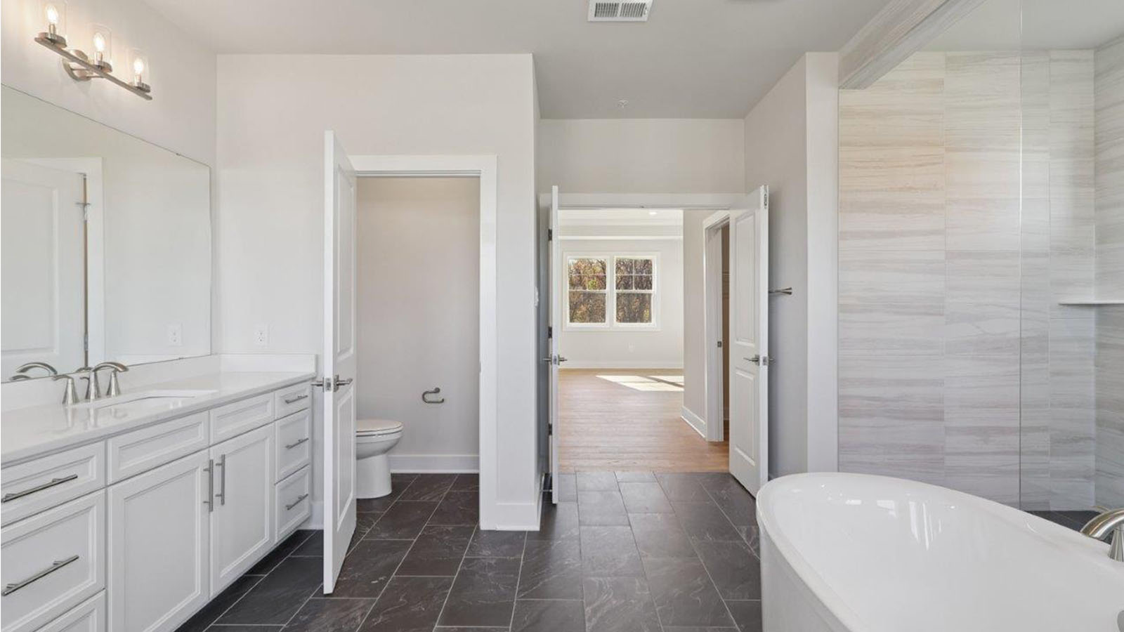 large primary suite with walk in closet and large full bathroom with double vanity, spacious shower and standing tub