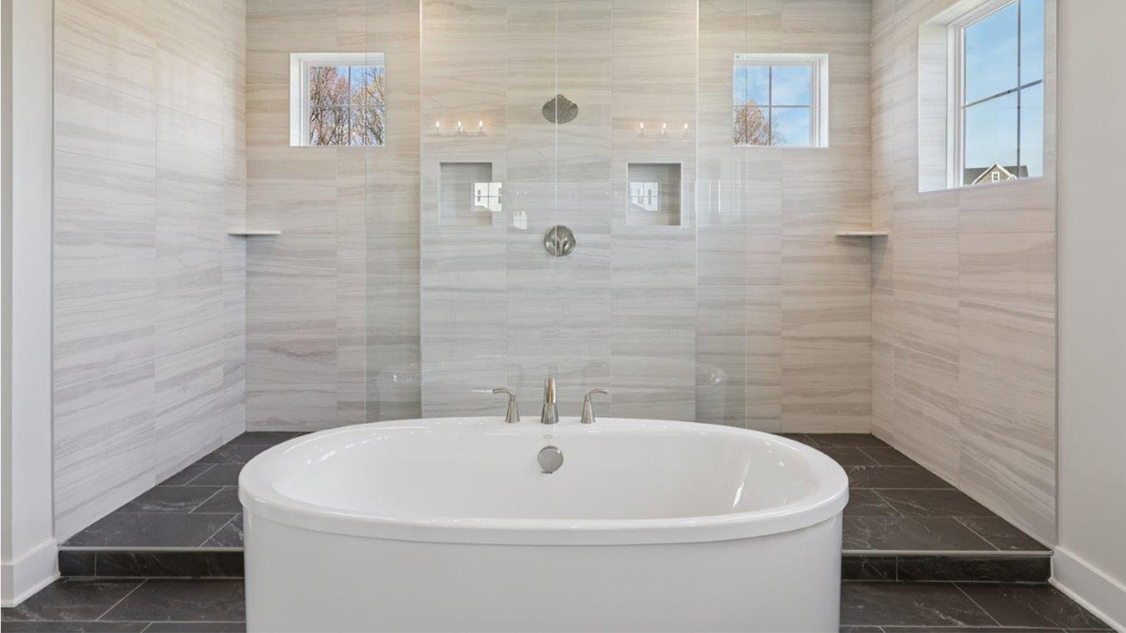 large primary suite with walk in closet and large full bathroom with double vanity, spacious shower and standing tub