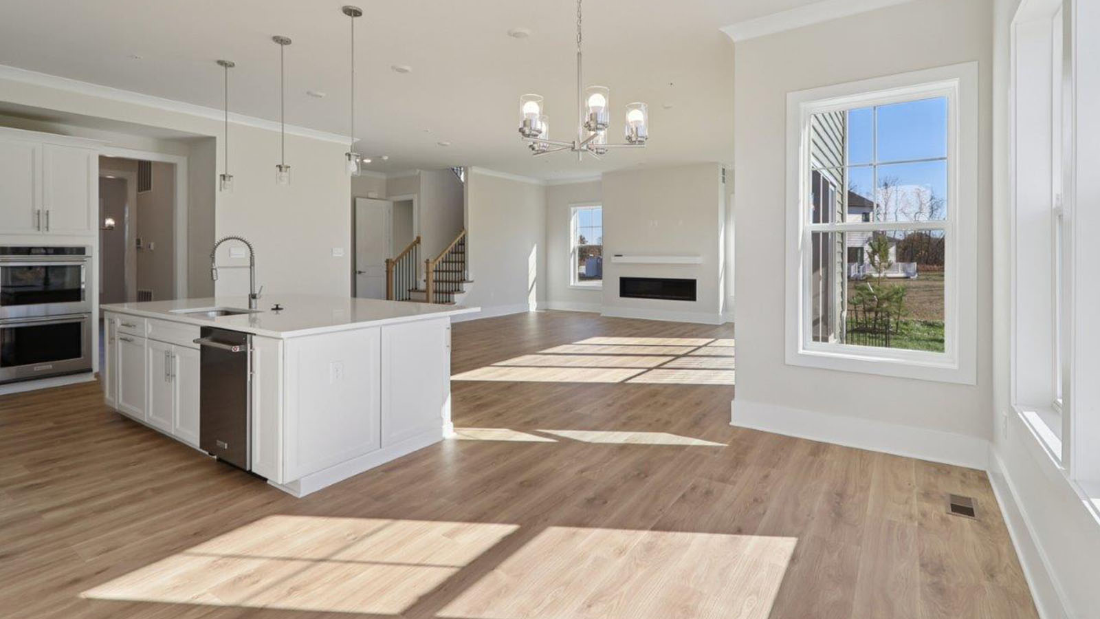 spacious kitchen with large quartz island and open concept living room behind