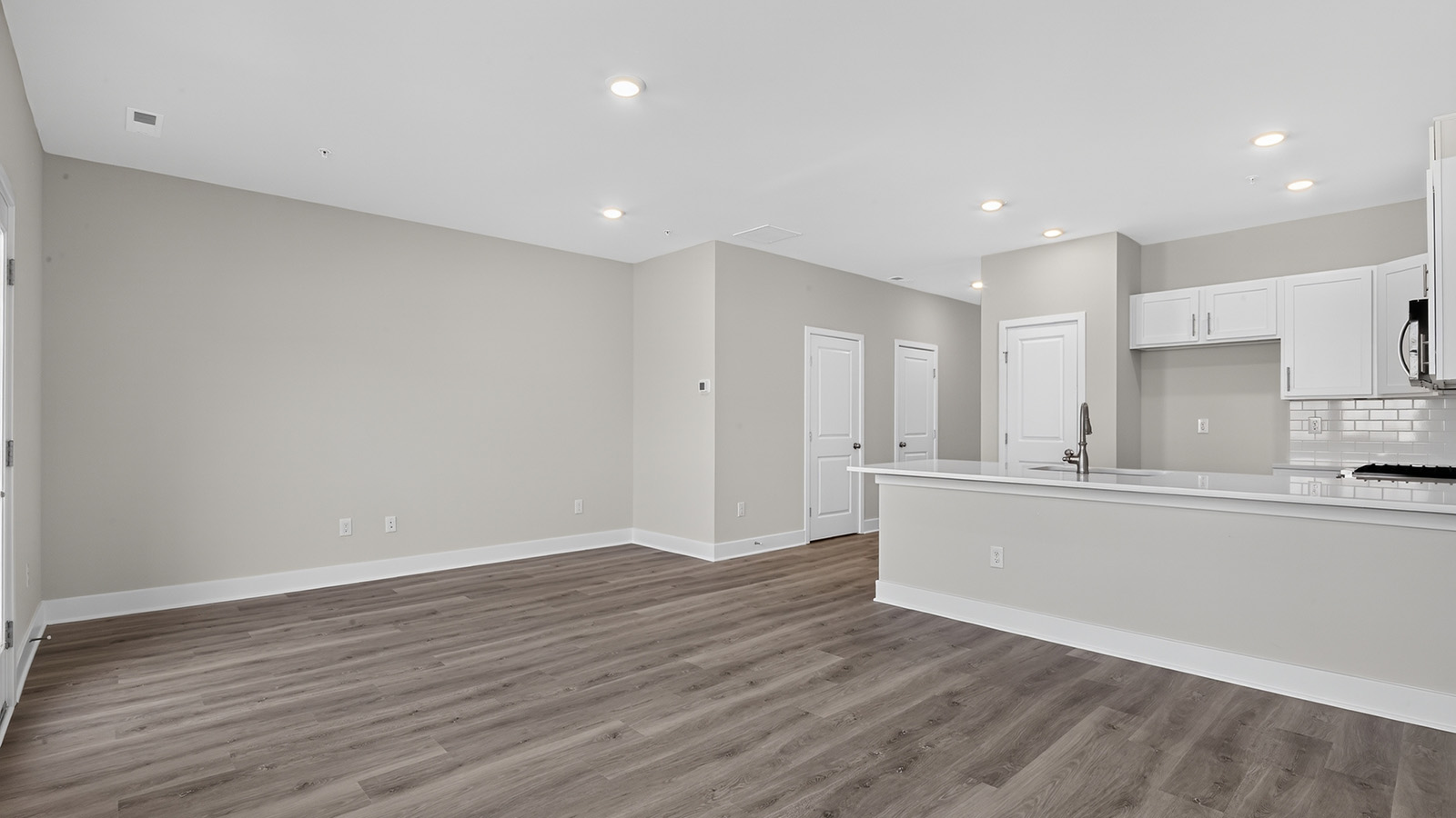 spacious open concept living room and kitchen with medium toned hardwood throughout