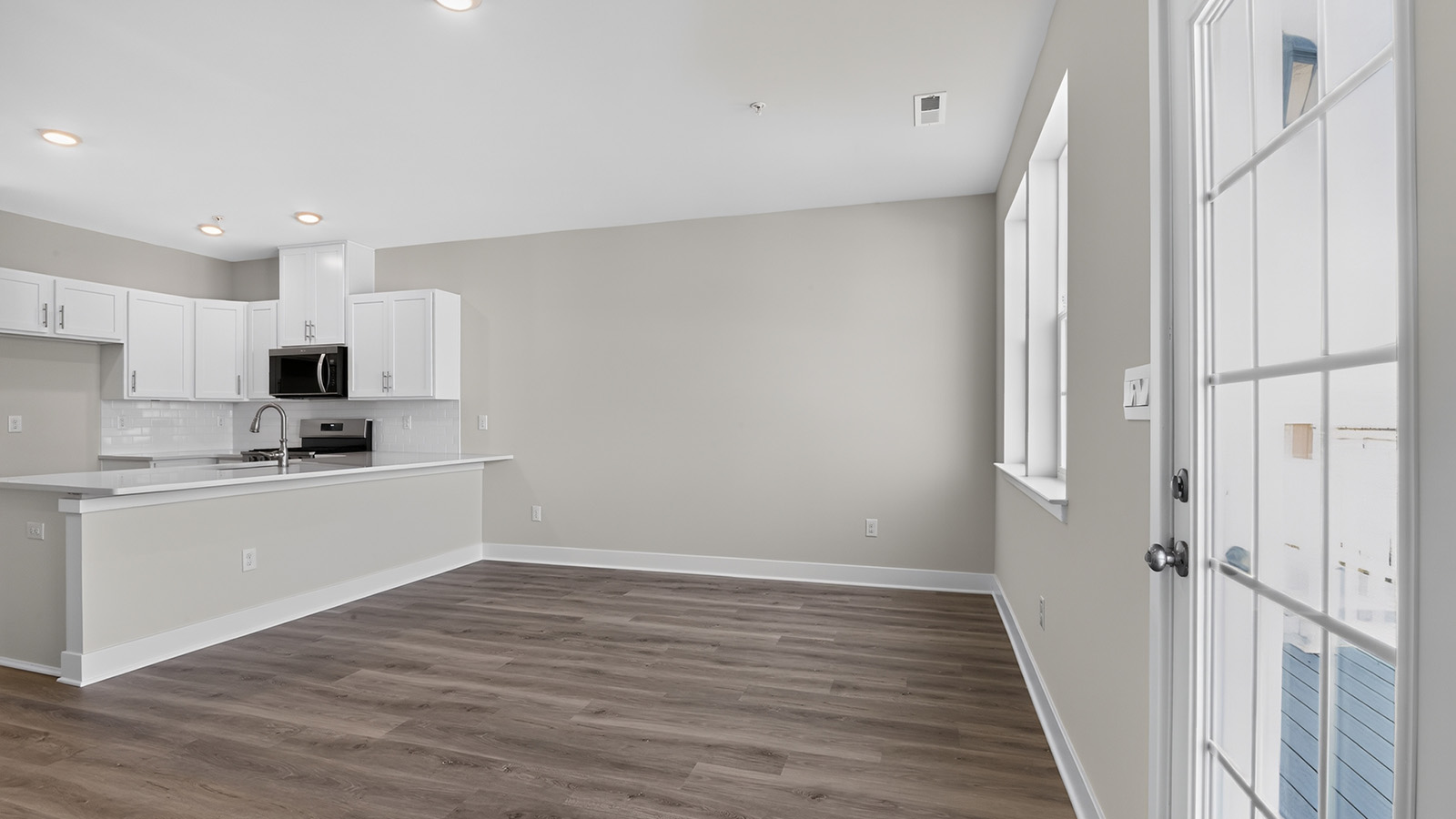 spacious open concept living room and kitchen with medium toned hardwood throughout