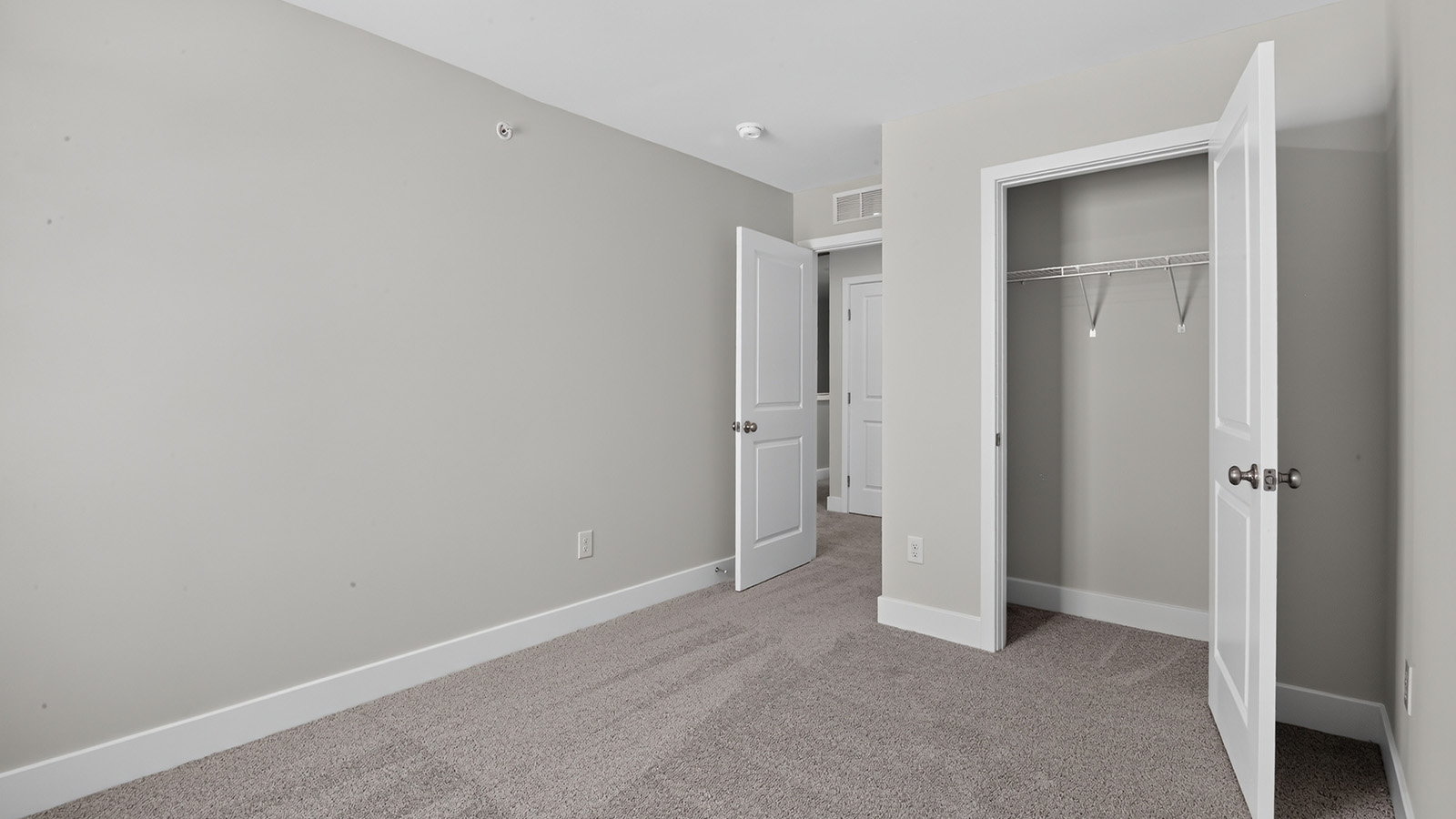 spacious bedroom with large windows and closet space