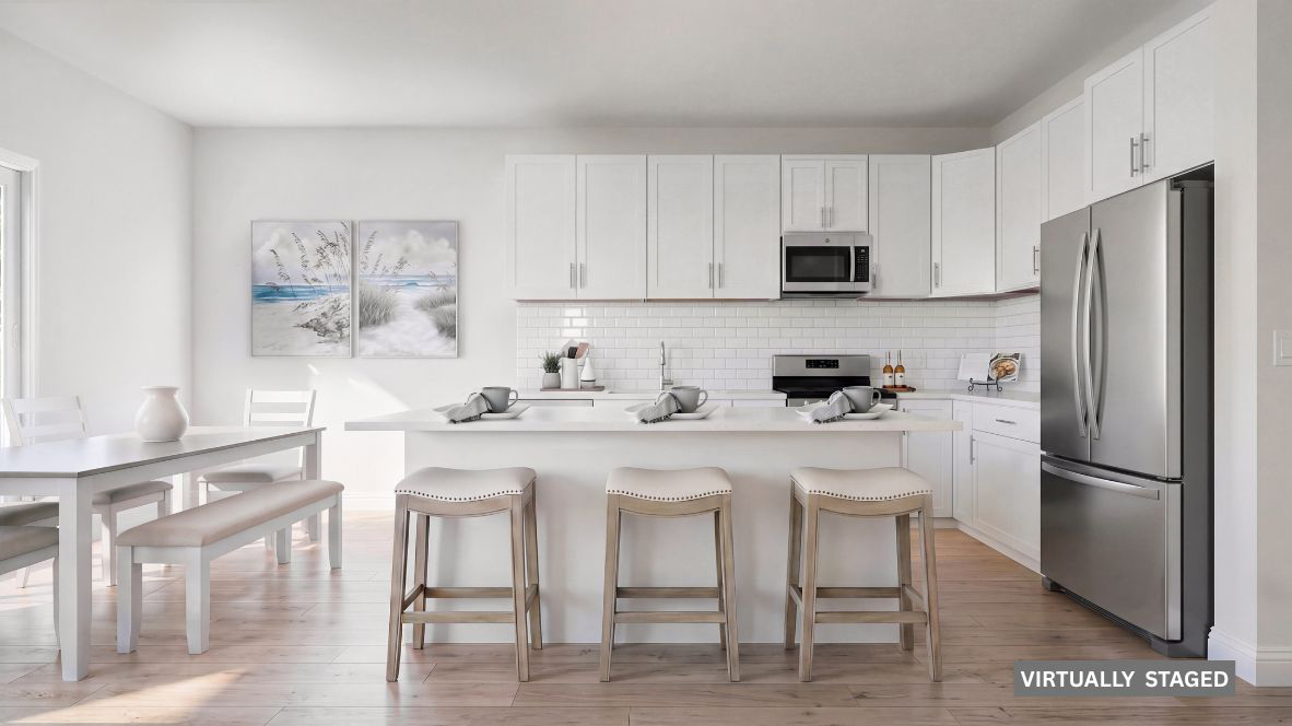 spacious kitchen with large quartz island, white cabinetry and stainless steel appliances