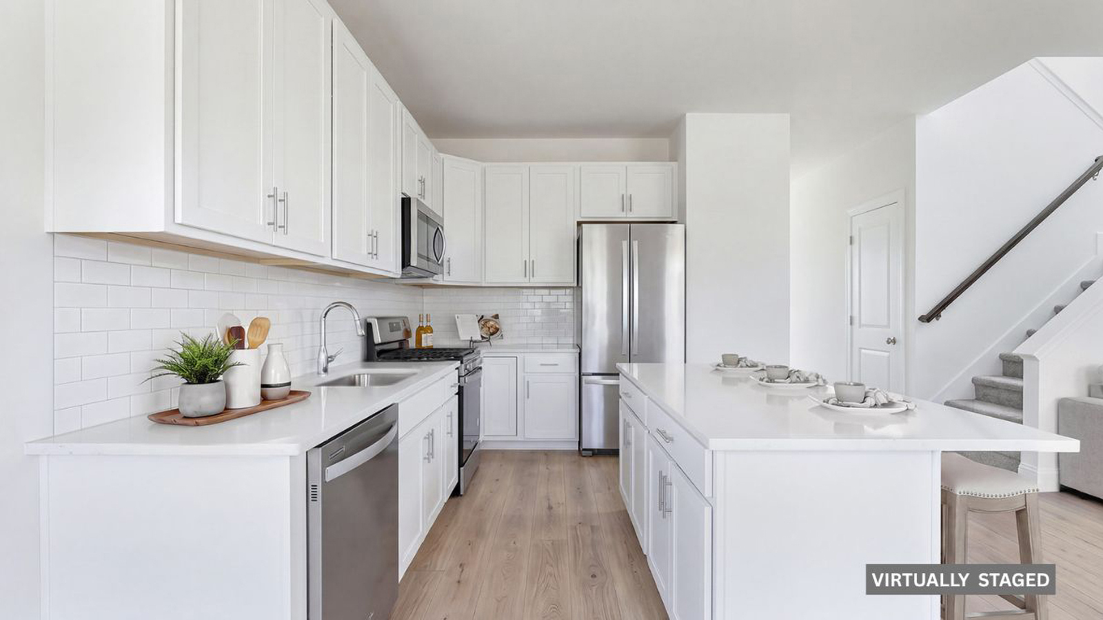spacious kitchen with large quartz island, white cabinetry and stainless steel appliances