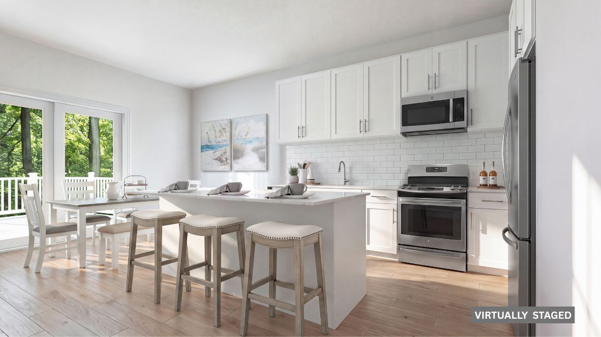 spacious kitchen with large quartz island, white cabinetry and stainless steel appliances