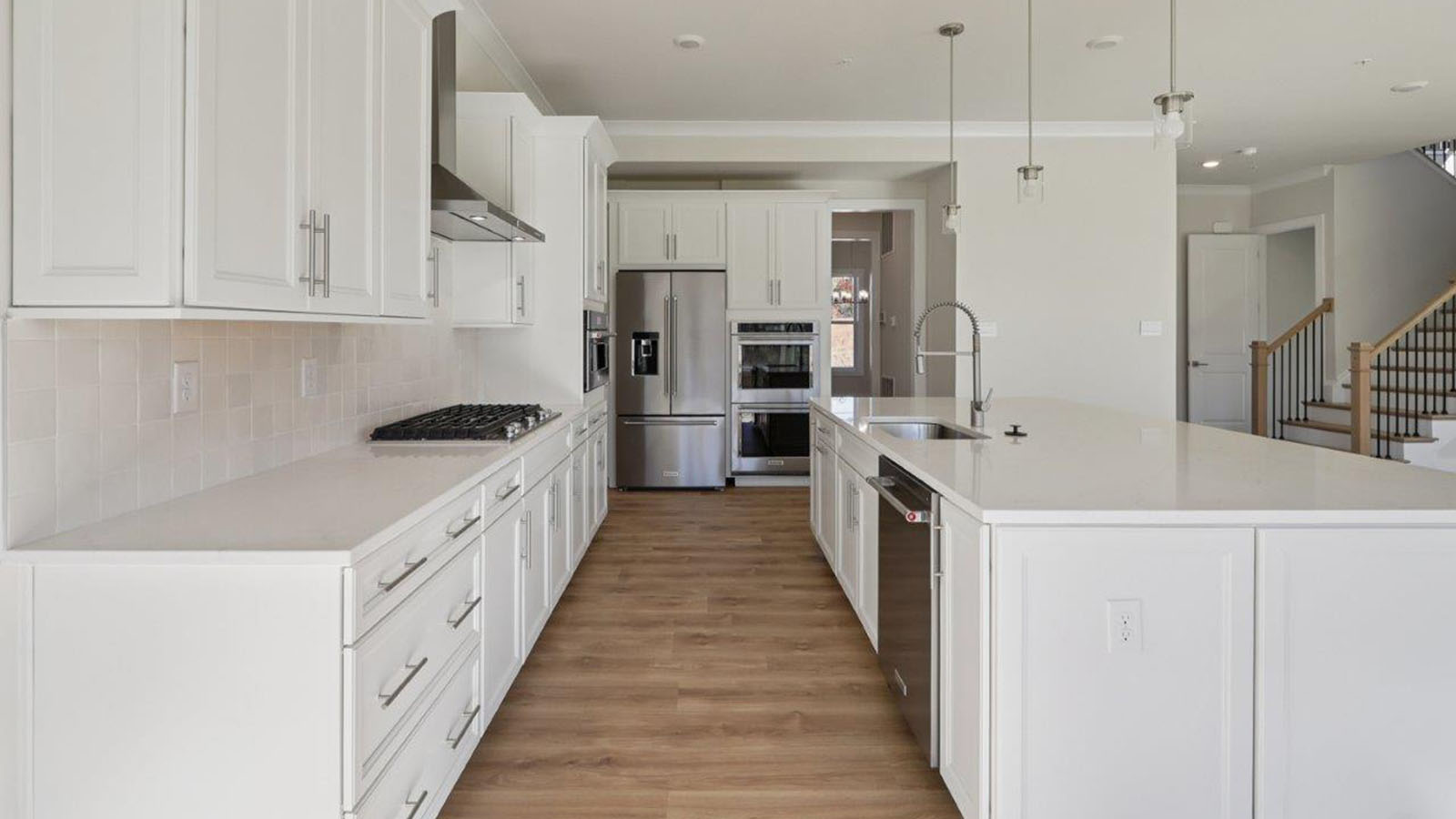 spacious kitchen with large quartz island and white cabinetry