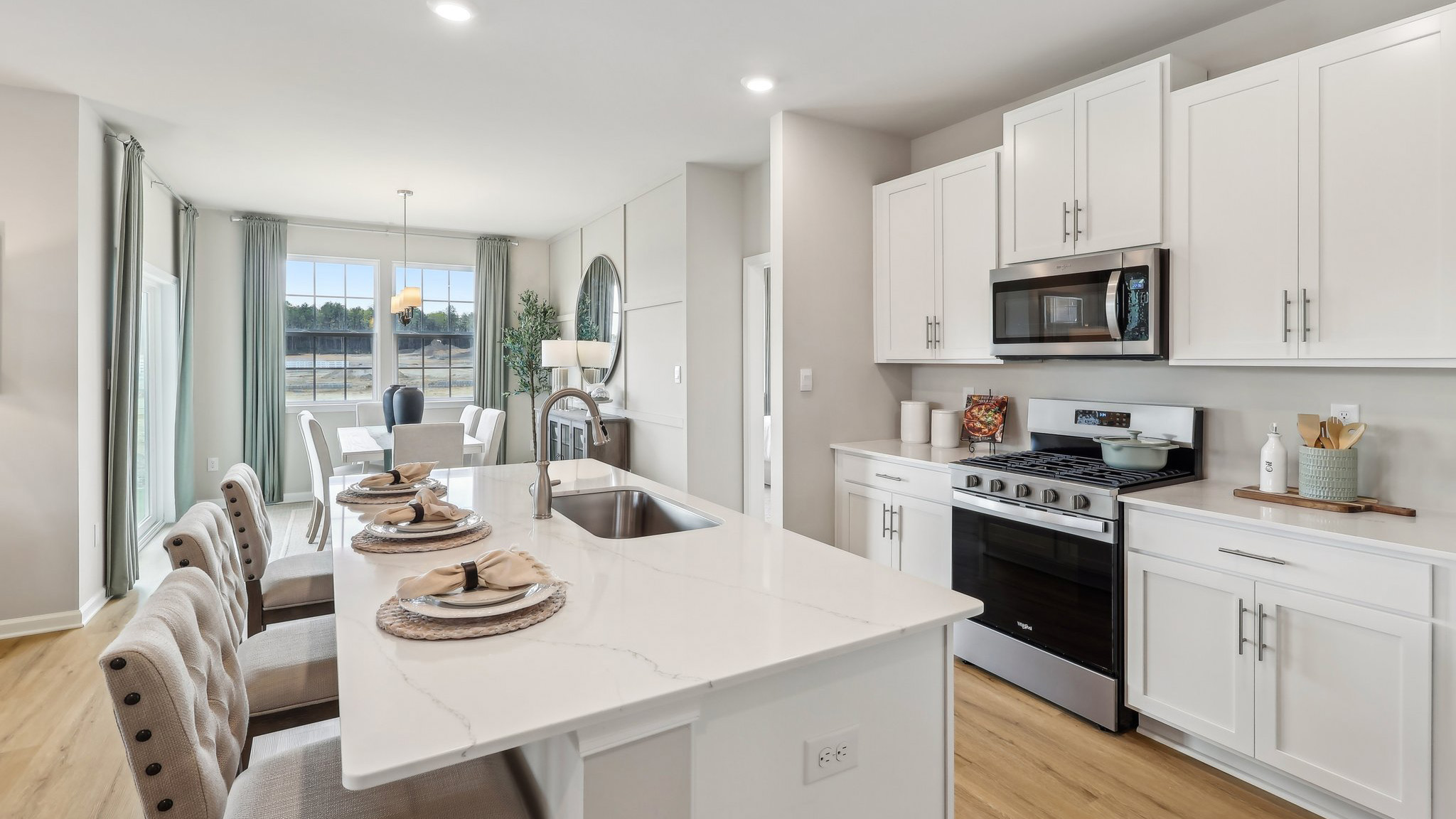 spacious island with quartz countertops, white cabinetry and stainless steel appliances