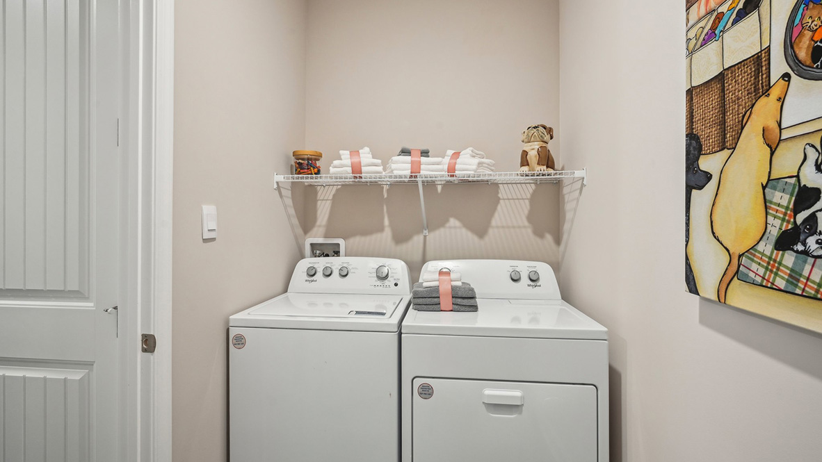 The large laundry room, tucked between the kitchen pantry and the three-car garage, also features a coat closet.
