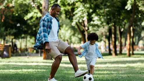 Dad with young son playing soccer