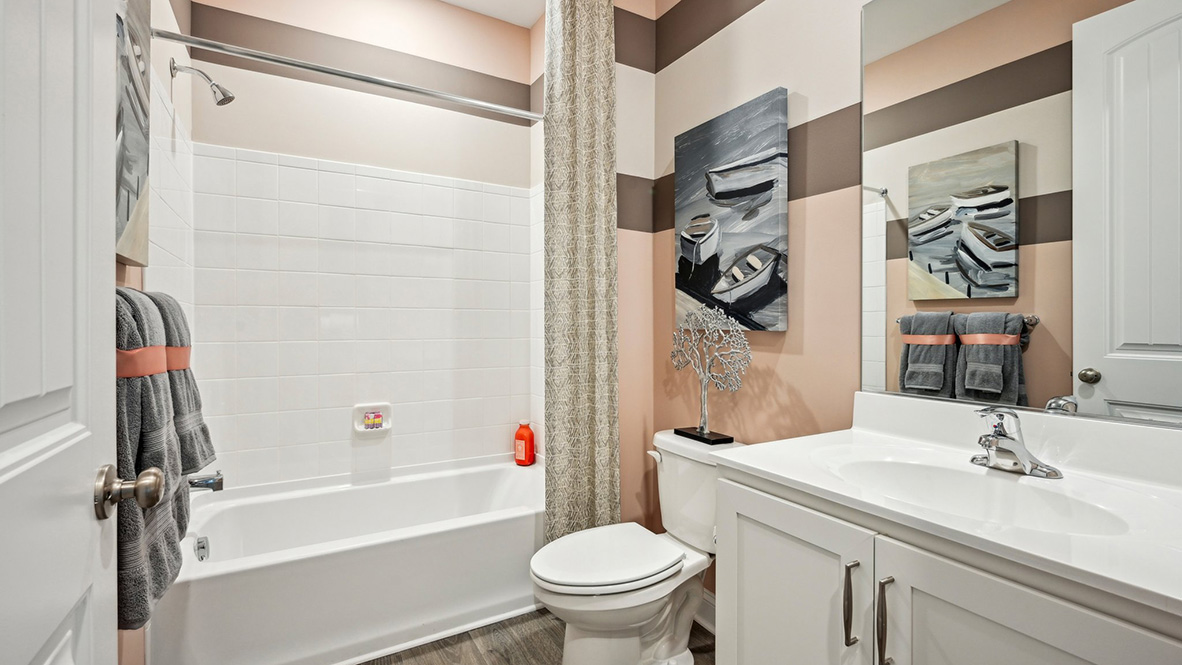 A full bath with a tub shower is next to a guest bedroom.