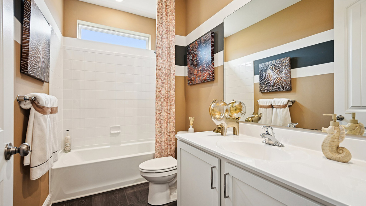 Inside the guest bathroom, there is a vanity, toilet, and a large window above the shower.