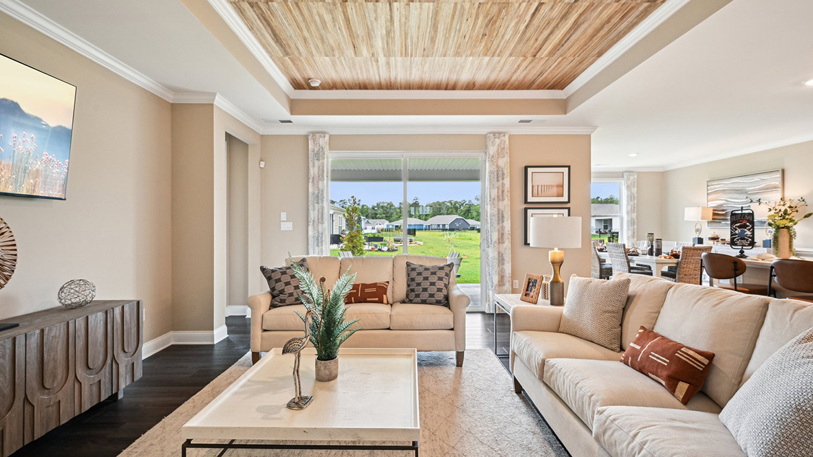 The open-concept great room with a tray ceiling leads you to the covered porch.