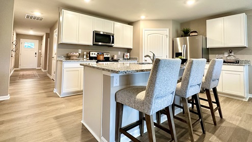 The open-concept kitchen has bright white kitchen cabinets.