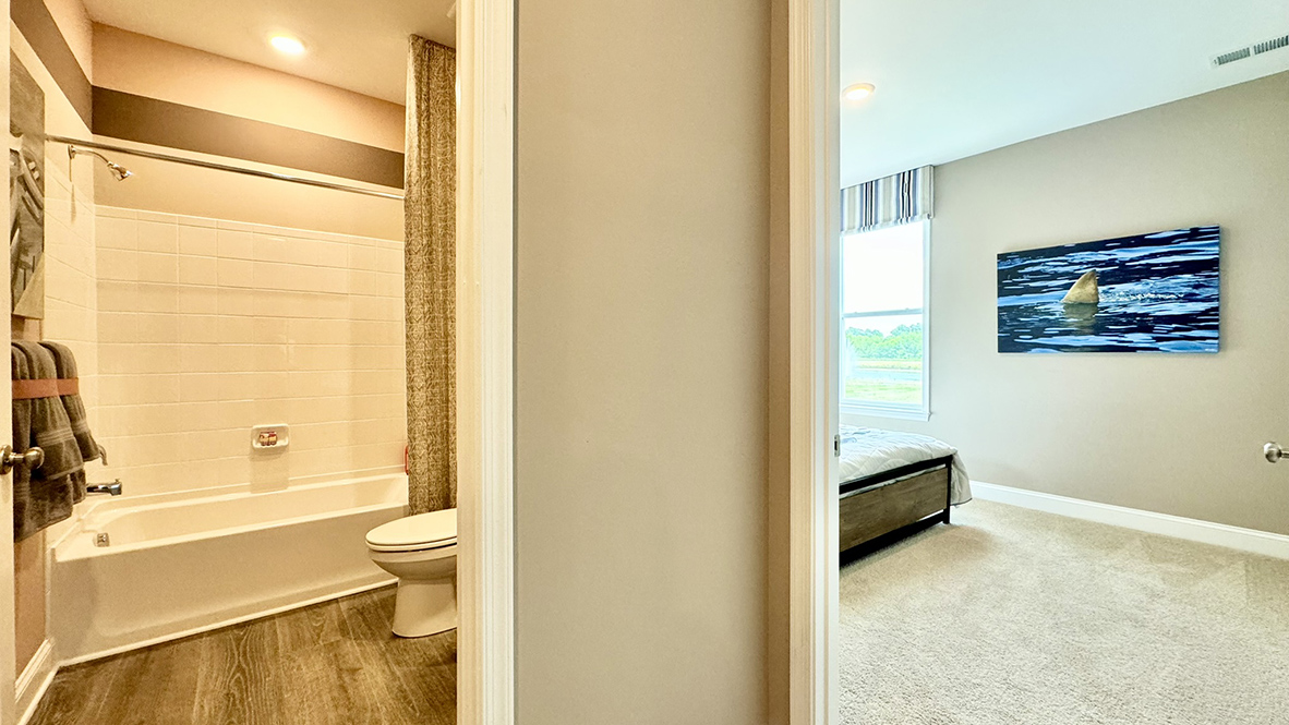 A full bath is next to a guest bedroom.
