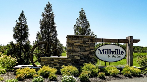 The Millville by the Sea entrance monument with a waterwheel and landscaping.