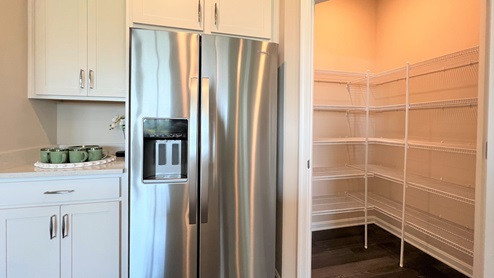 In the corner of the kitchen is a walk-in pantry closet.