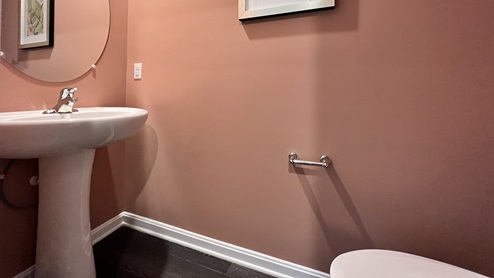 The powder room is located in the hallway leading to the two-car garage.
