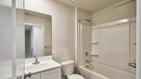 The secondary bathroom is equipped with a shower tub, toilet and vanity.