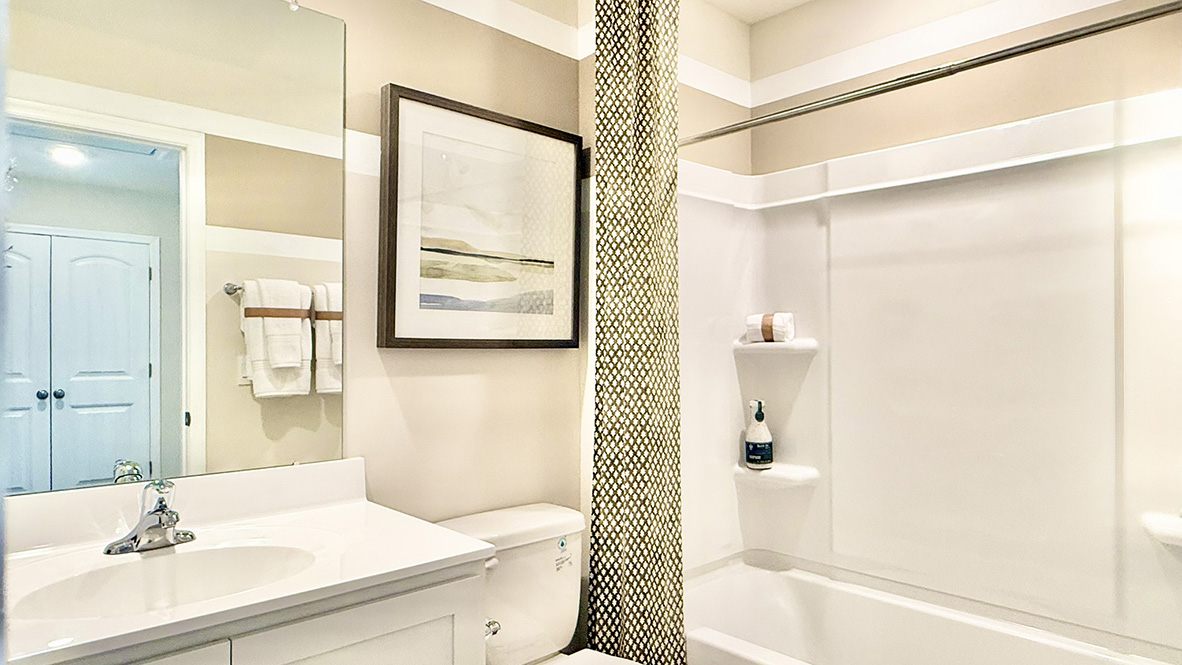 A guest bathroom with a vanity and tub shower is located down the hallway.