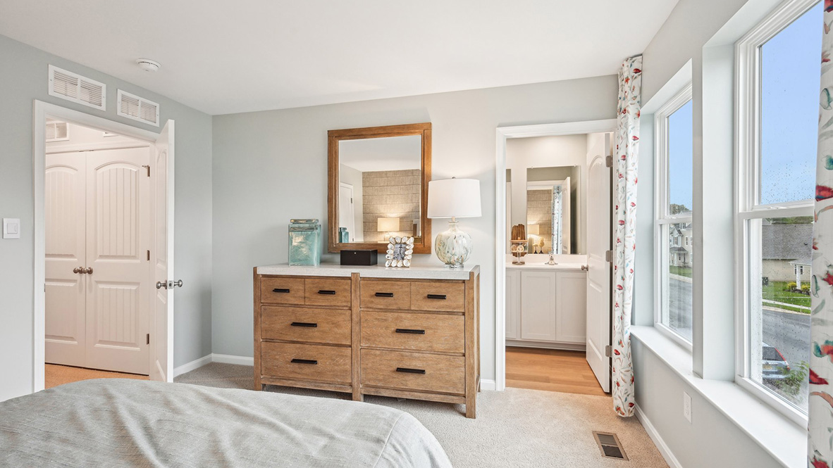 Another view of the primary bedroom with an ensuite bathroom and walk-in closet.