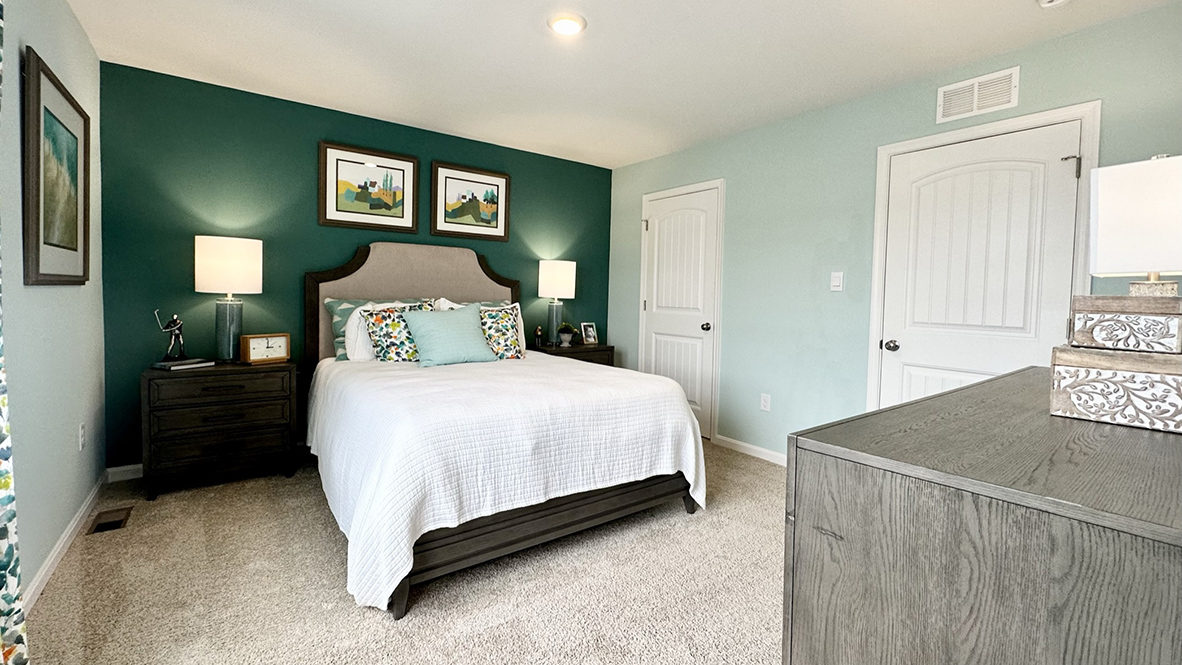 Another view of the primary bedroom with an ensuite bathroom and walk-in closet.