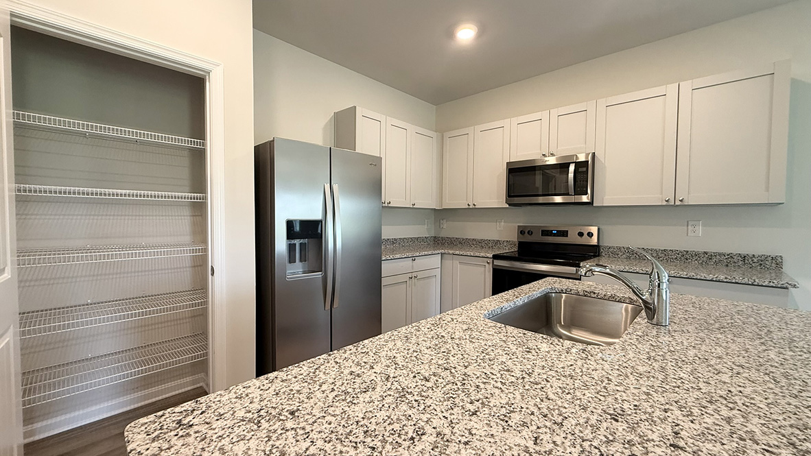 The well-appointed kitchen features an abundance of cabinetry, stainless steel appliances, a pantry and an island with additional room for seating.