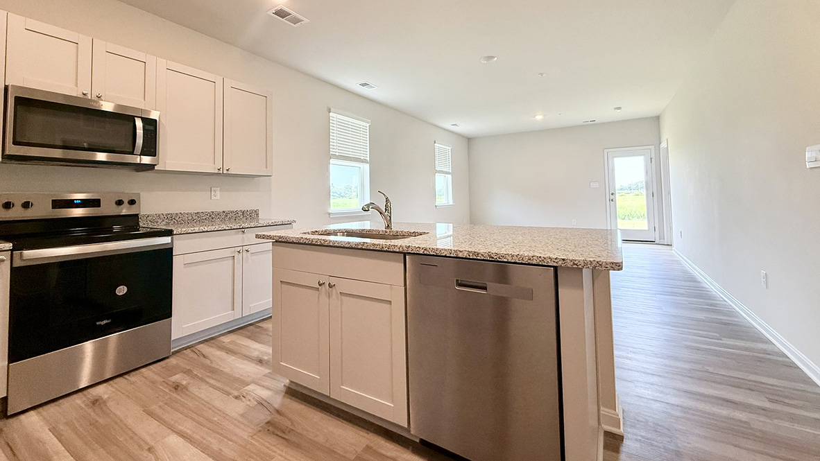 The well-appointed kitchen features an abundance of cabinetry, stainless steel appliances, a pantry and an island with additional room for seating.