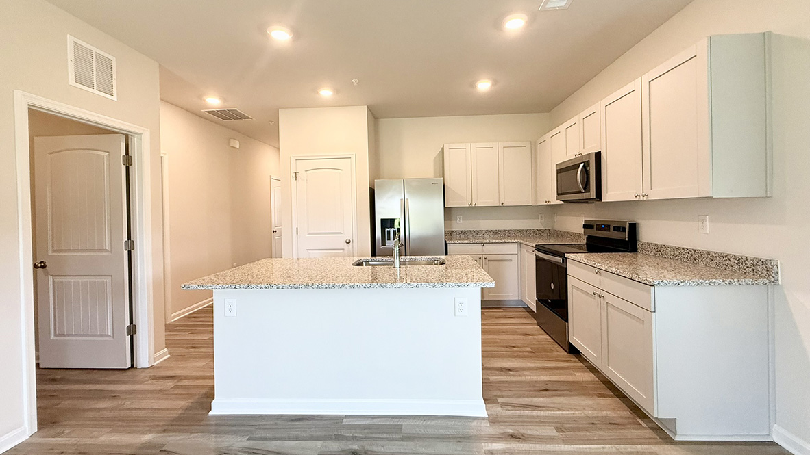 The well-appointed kitchen features an abundance of cabinetry, stainless steel appliances, a pantry and an island with additional room for seating.