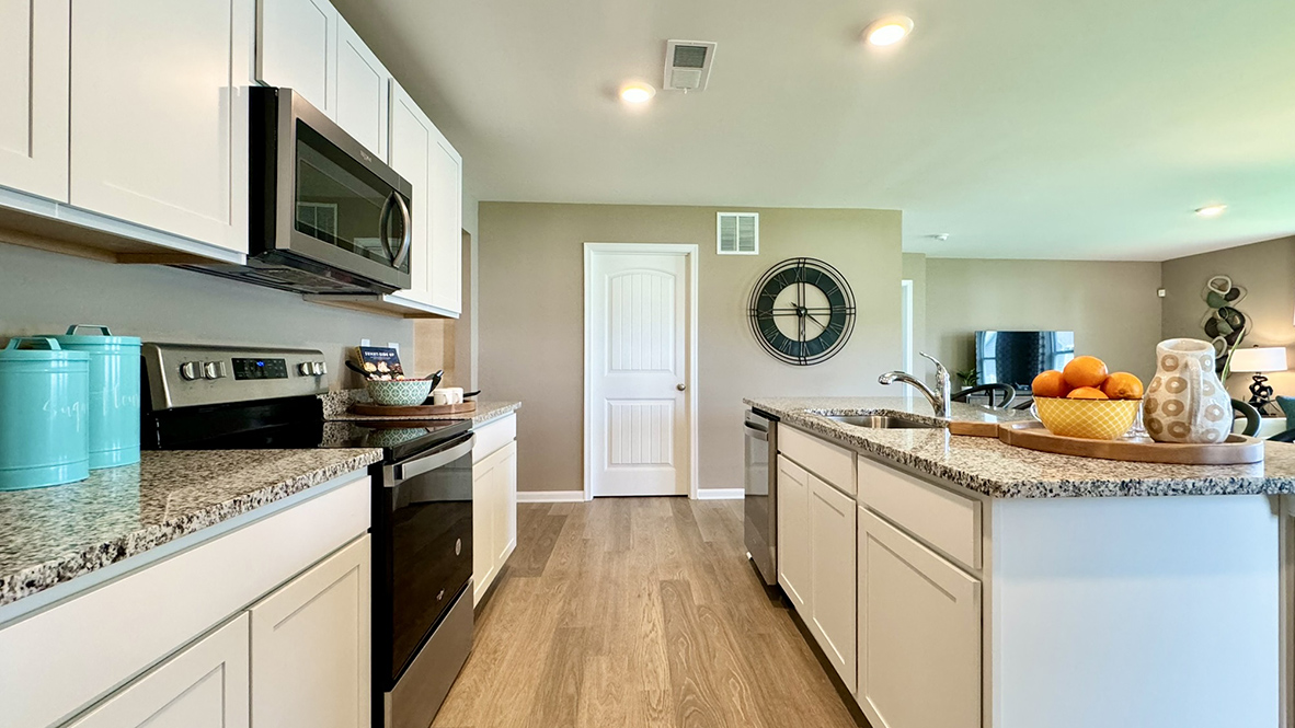 A large kitchen island with a sink is centered in the kitchen.