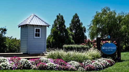 A Millville by the Sea sign with summer flowers beds in full bloom.