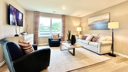 The cozy living area has a double window and laminate plank flooring.