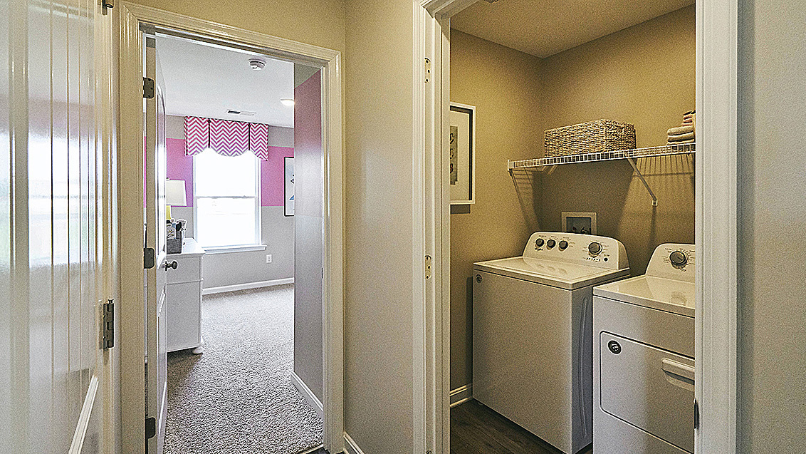 The laundry room, complete with a washer and dryer, is nestled near the two-garage.