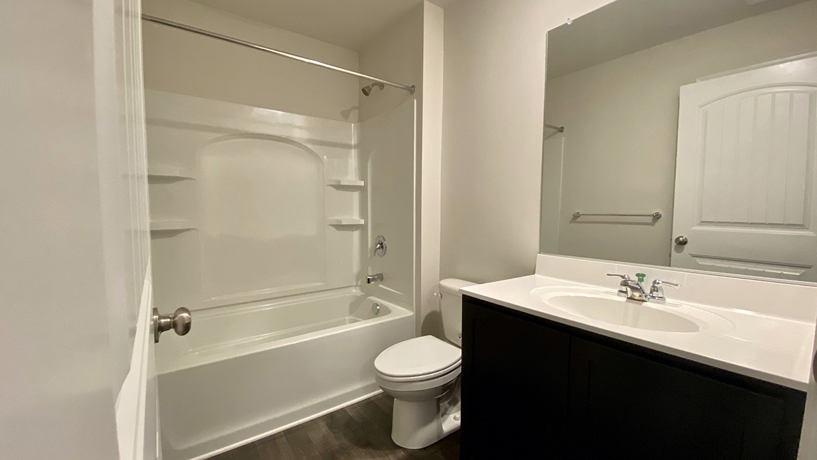 The guest bathroom has a tub shower, toilet and vanity.